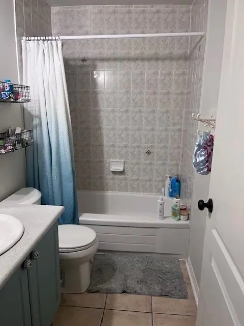 Original bathroom before renovation with older wall tile, tub surround and flooring