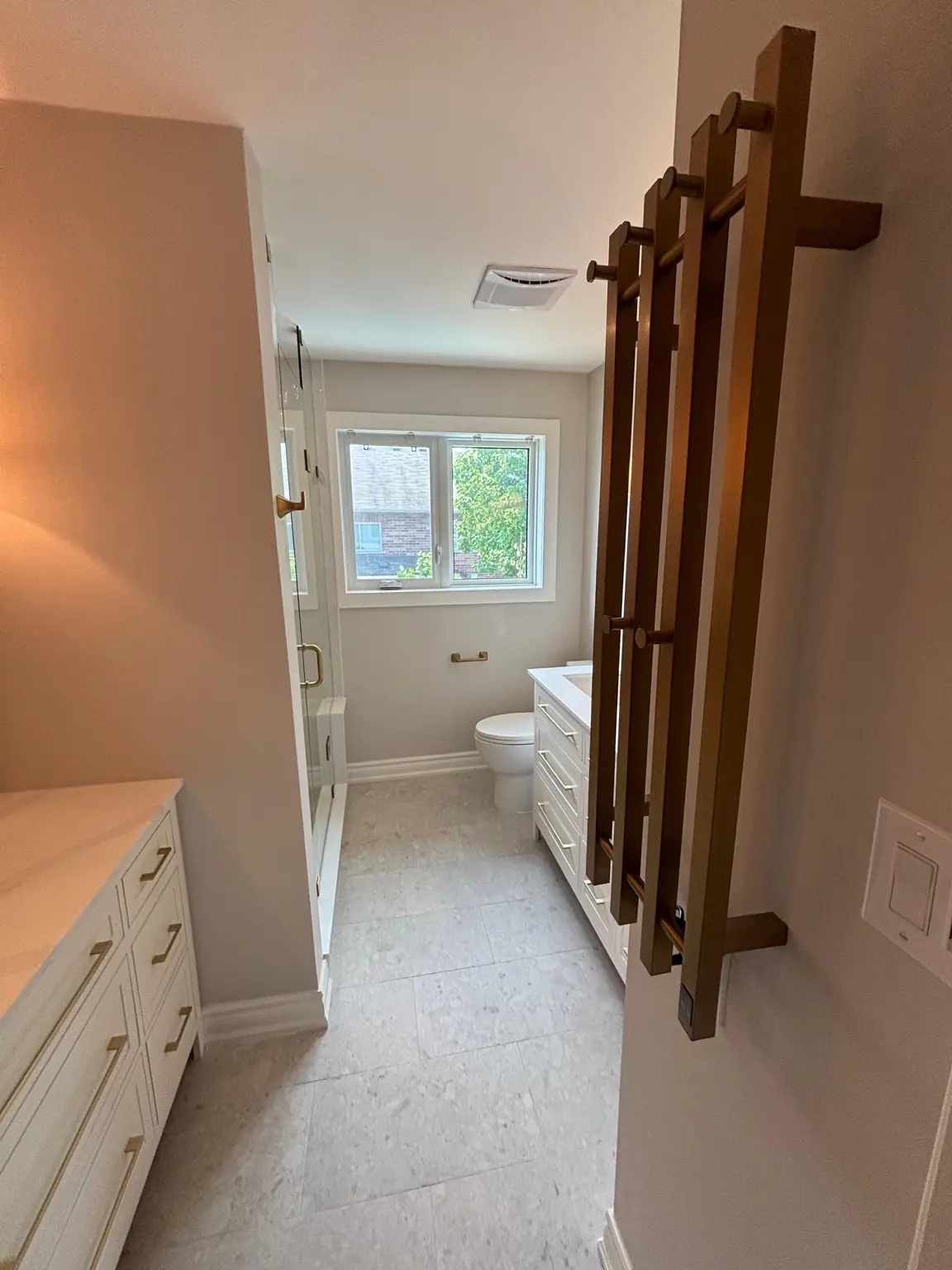 Finished bathroom with custom cabinetry, double vanity, tiled floor and brass towel warmer