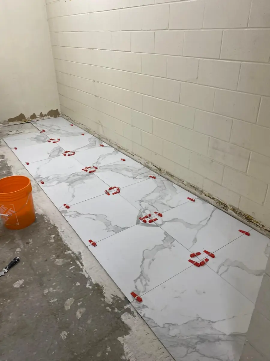 Commercial washroom floor tiles being installed with levelling clips